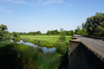 old stone bridge and river side fields on a sunny day
