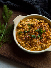 Rustic carrot hummus on wooden board.