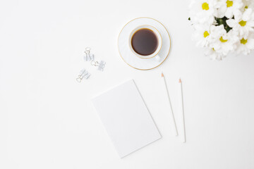 Mockup white notebook, white flowers, a cup of coffee on a white background