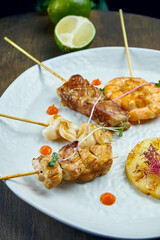 Assorted Asian Street Snacks - Satay. Grilled chicken, pork, squid and shrimp on a white plate. Selective focus