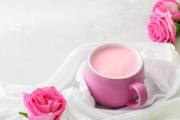 Cup of moon milk with a roses on on light concrete. Ayurvedic relaxing drink for the night.