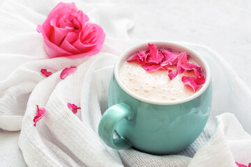 Cup of moon milk with a roses on on light concrete. Ayurvedic relaxing drink for the night.