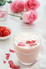 Glass of moon milk with a roses on on light concrete. Ayurvedic relaxing drink for the night.