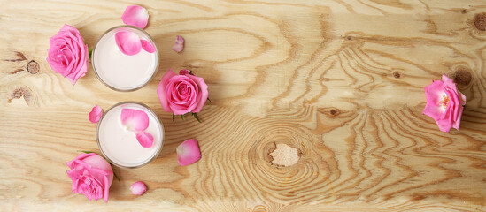 Glasses of moon milk with a roses on wooden table. Ayurvedic relaxing drink for the night.