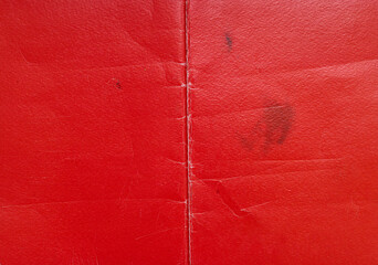 detail shot of old red school or textbook with flaws and kinks, cool vintage paper surface.
