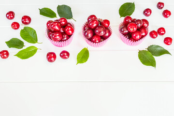 ripe cherry berries in pink molds on a white background close-up. cherries and copy space. background with cherry berries and green leaves. ripe red cherry berries on a white background.