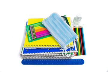 Stack of school supplies including Covid 19 face masks  on a white background