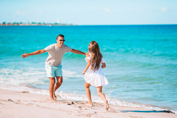 Naklejka premium Little girl and happy dad having fun during beach vacation