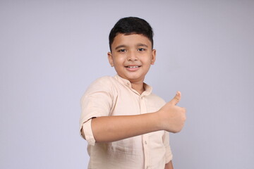 Cute Indian boy showing thumbs up or all done or like hand gesture. Isolated over white background.
