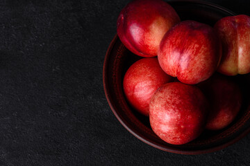 Delicious sweet peaches or nectarines in a brown bowl