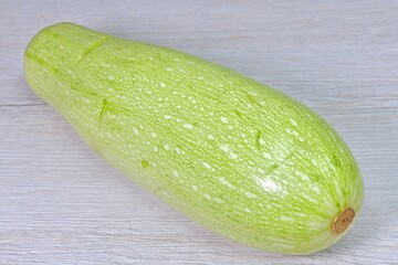 isolated fresh zucchini in peel on a light wooden surface