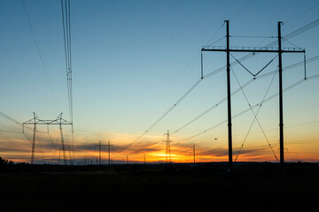 Fototapeta na wymiar High-voltage power lines at sunset by the road. Horizontal