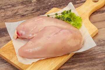 Raw chicken breast over board