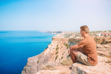 Tourist man outdoor on edge of cliff seashore