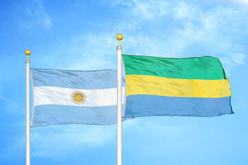 Argentina and Gabon two flags on flagpoles and blue sky