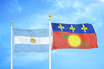 Argentina and Guadeloupe two flags on flagpoles and blue sky