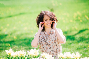 Young attractive woman with curly long hair posing in spring blooming garden, apple trees