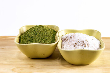 set of spices in a ceramic bowl of salt crystals and chopped dried parsley dill stands on a wooden table on a white background