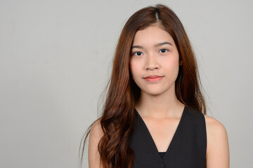 Portrait of young beautiful Asian woman against white background