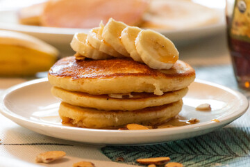 Obraz na płótnie Canvas delicious banana pancake breakfast topped with almonds, syrup, and bananas
