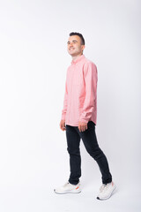 Photo of cheerful young man in red shirt walking over white background.