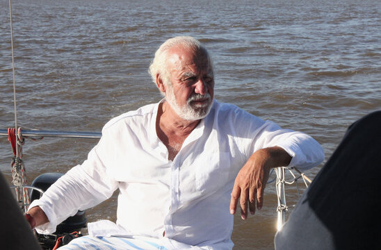 Hombre de tercera edad sentado en un barco, contemplando la vista.