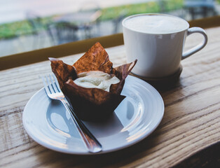 Coffee and a cinnamon roll at a window side table at a cafe.