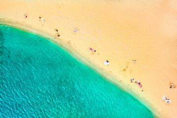 Top view of the azure coast with beautiful water and people resting on the shore. Yellow warm sand and azure clean water.