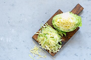 Fresh young cabbage on a wooden kitchen board for shredding on a blue background. Vegetables for...