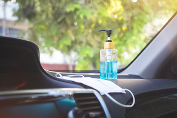 Han gel sanitizer and surgical facemask placed on car concole in a car