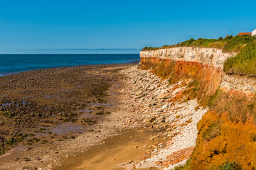 A view from cliff top across the beach and along the white, red and orange stratified cliffs at Old Hunstanton, Norfolk, UK