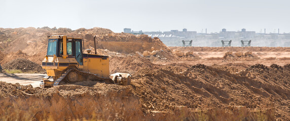 bulldozer heavy machinery transport raking clay for landscape planning before construction, yellow crawler tractor doing work moving earth, nobody. © Александр Беспалый