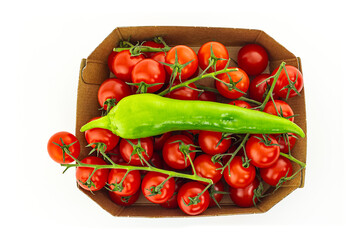 red tomato many vegetables with green pepper in a cardboard basket on a white isolated background