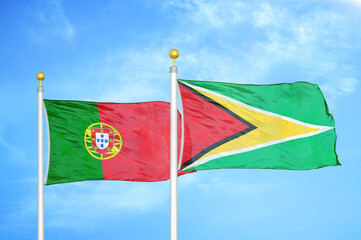 Portugal and Guyana two flags on flagpoles and blue sky