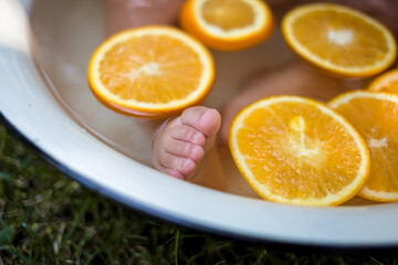 baby's foot in a tub of oranges