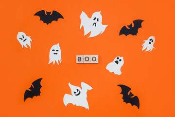 Word Boo. Wooden blocks with letters on orange background decorated with bats and ghosts from cardboard. Top view