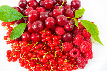 Assorted red fresh berries on a plate on a white background.
