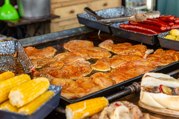 summer cafe tray full of meat seasoned chicken piece, corn cob and sausage