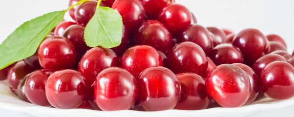 Many fresh ripe cherries on a white plate. Selective focus.