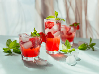 Glasses of strawberry cocktail or mocktail, refreshing summer drink with crushed ice and sparkling water on a light background. Beverage photography.