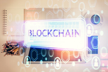 Blockchain theme hologram drawings over computer on the desktop background. Top view. Double exposure.
