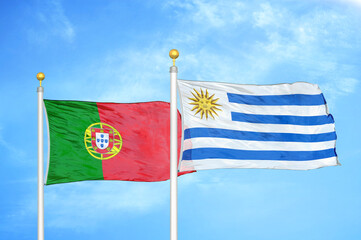 Portugal and Uruguay two flags on flagpoles and blue sky