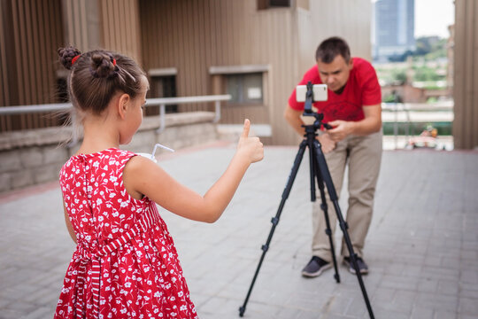 Make money online. Father recording film with daughter for family channel, video blogger