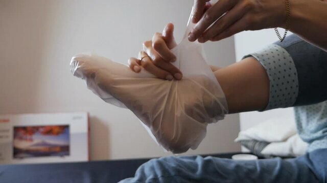 Moisturizing foot mask for dry heels. Woman wearing moisturizing sock mask on her feet