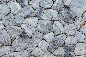 stone wall of multifaceted cobblestones, pebbles dark pattern