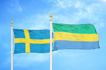 Sweden and Gabon two flags on flagpoles and blue sky
