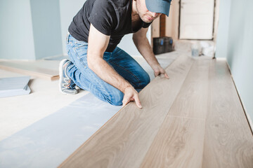 Close-up of the work of a master floating flooring installation - installing laminate on the floor...