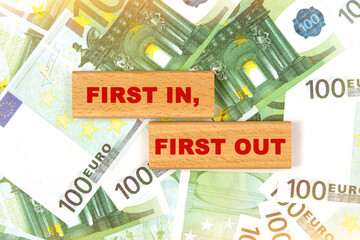 Against the background of euro bills, the text is written on wooden blocks - first in first out