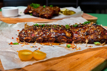 Close up board with pork ribs grilled with BBQ sauce, peanuts and jalapeno
