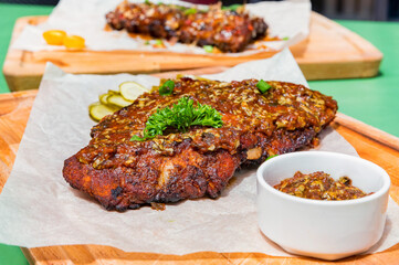 Close up board with pork ribs grilled with BBQ sauce, peanuts and jalapeno